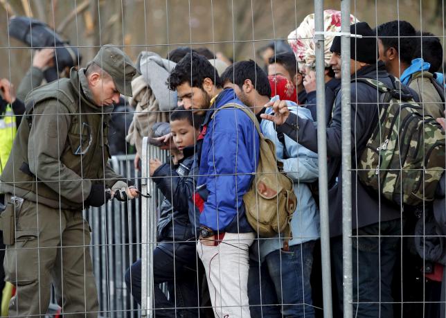 An Austrian soldier fixes the fence as migrants wait to cross the border into Spielfeld in Austria from the village of Sentilj, Slovenia, October 31, 2015. REUTERS/Srdjan Zivulovic