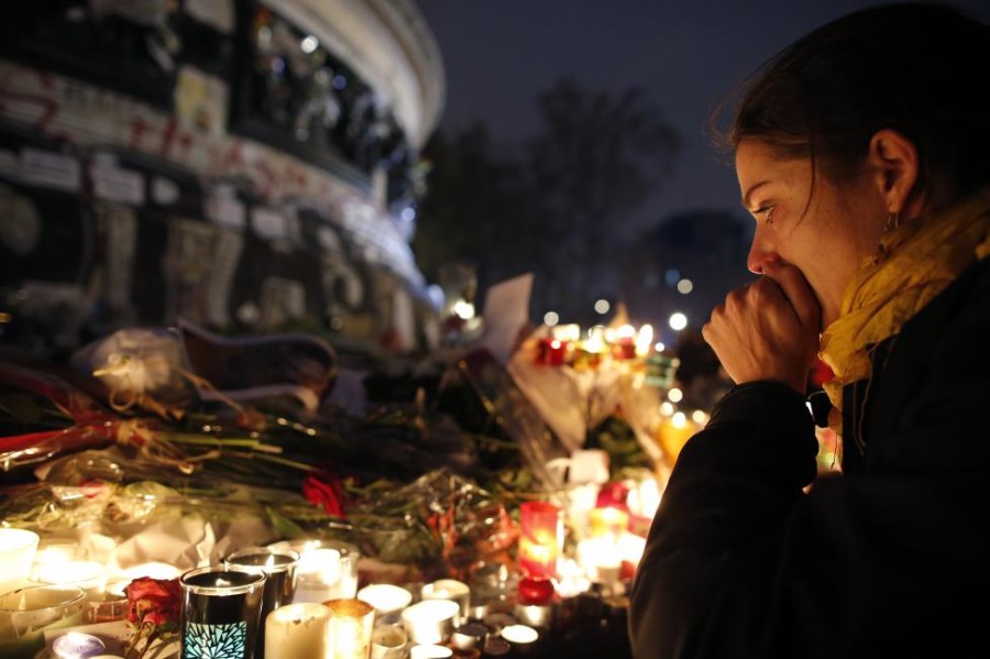 A woman weeps as she kneels near bouquets of flowers and burning candles at the Place de la Republique in Paris, France, November 16, 2015, as people continue to pay tribute to the victims of the series of deadly attacks in the French capital on Friday. REUTERS/Christian Hartmann